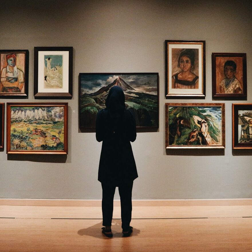 woman in black coat standing in front of paintings